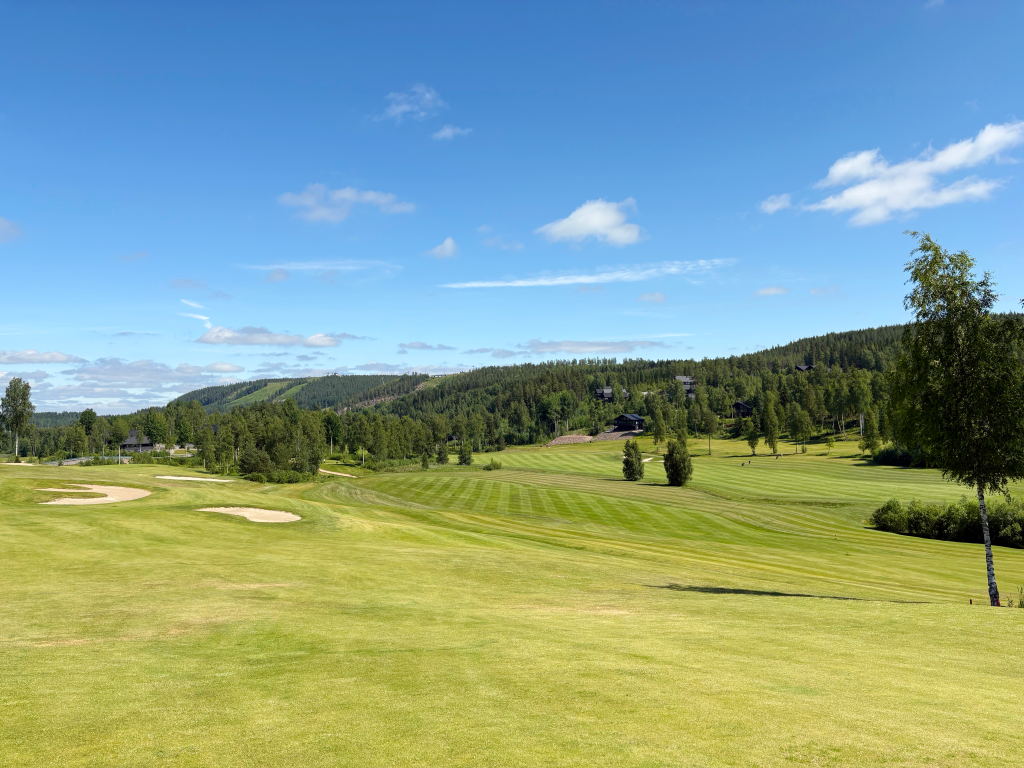 Himos Golf huippukunnossa. Kuva vihreältä Himoksen golfkentältä, taustalla näkyy kesäiset laskettelurinteet.
