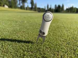 Himos Golf -logolla varustettu greenihaarukka pystyssä viheriöllä.